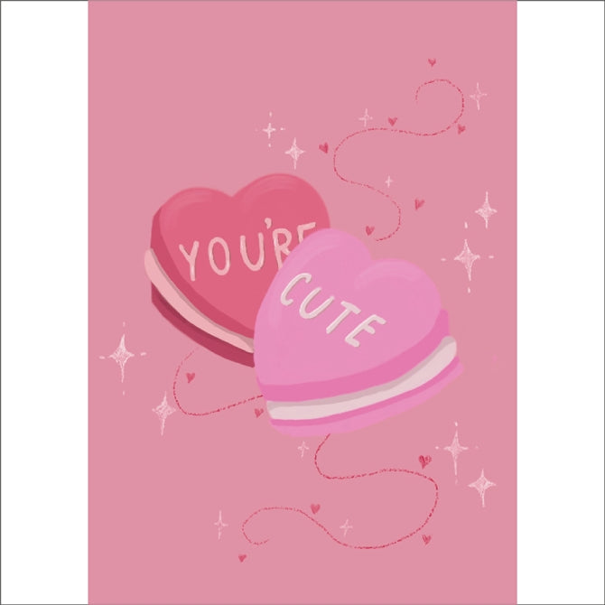 Soft pink A6 card featuring two heart shaped macarons with the words "YOU'RE CUTE" on.